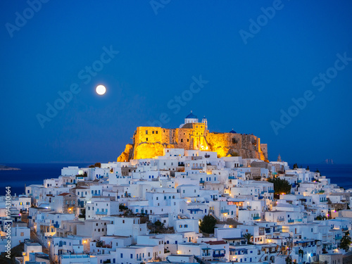 Chora of Astypalaia in blue hour with the full moon rising behind the enlightened fortress photo