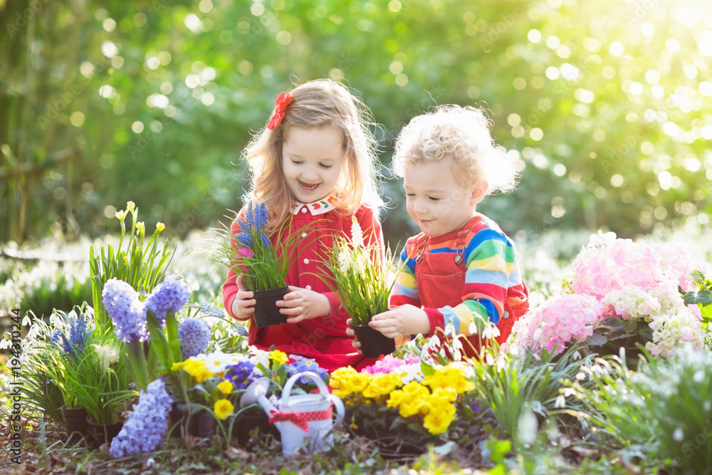 Kids plant and water flowers in spring garden