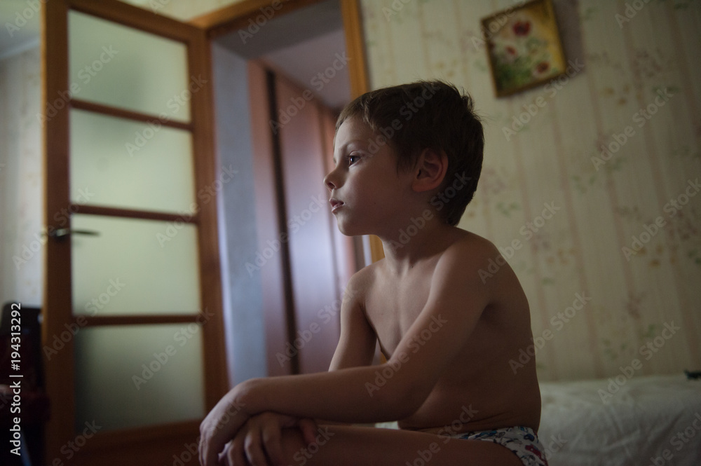 Fototapeta premium lonely sad little kid sitting in the room with no clothes on