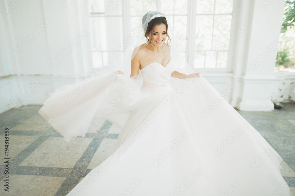 Beautiful bride in wedding dress with long full skirt, white background, dance and smile Beautiful bride in wedding dress with long full skirt, white background, dance and smile