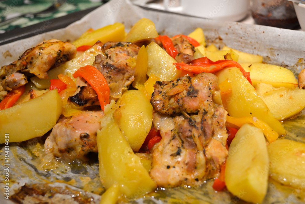 Potatoes with meat and vegetables baked in the oven on baking paper. Close-up Potatoes with meat and vegetables baked in the oven on baking paper. Close-up