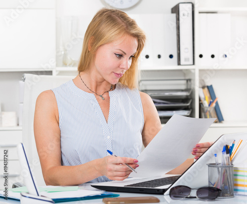 portrait of business woman writing and working with laptop in office