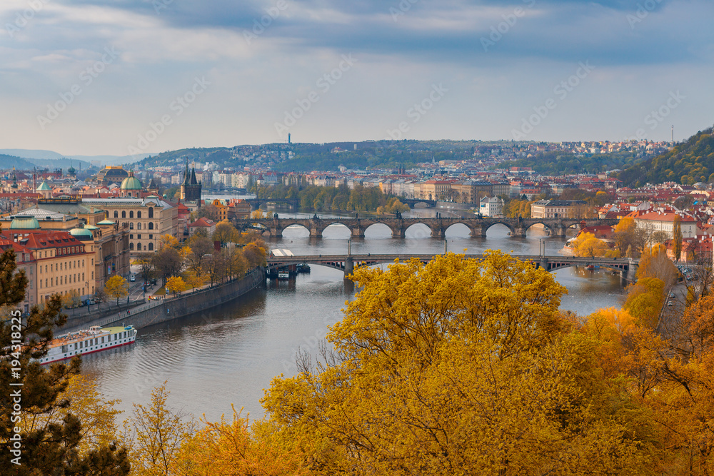 Scenic aerial view of the Old Town architecture and bridge over Vltava river in Prague, Czech Republic. Trees of the park at the foreground, fall time