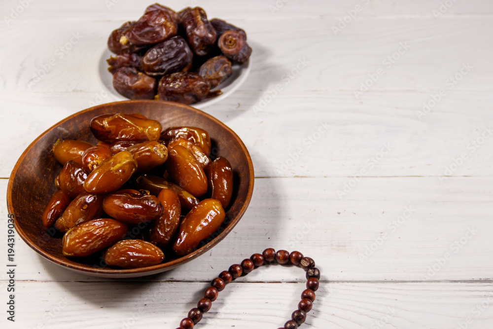 Dates fruit and rosary on white wooden table