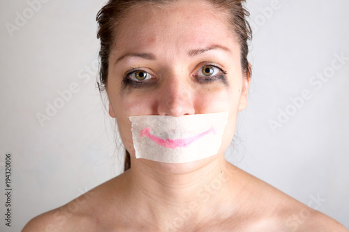 Unhappy woman with wrapping her mouth by adhesive tape painted smile photo