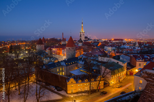 Exciting winter view of night old town of Tallinn. Aerial over roofs and towers.