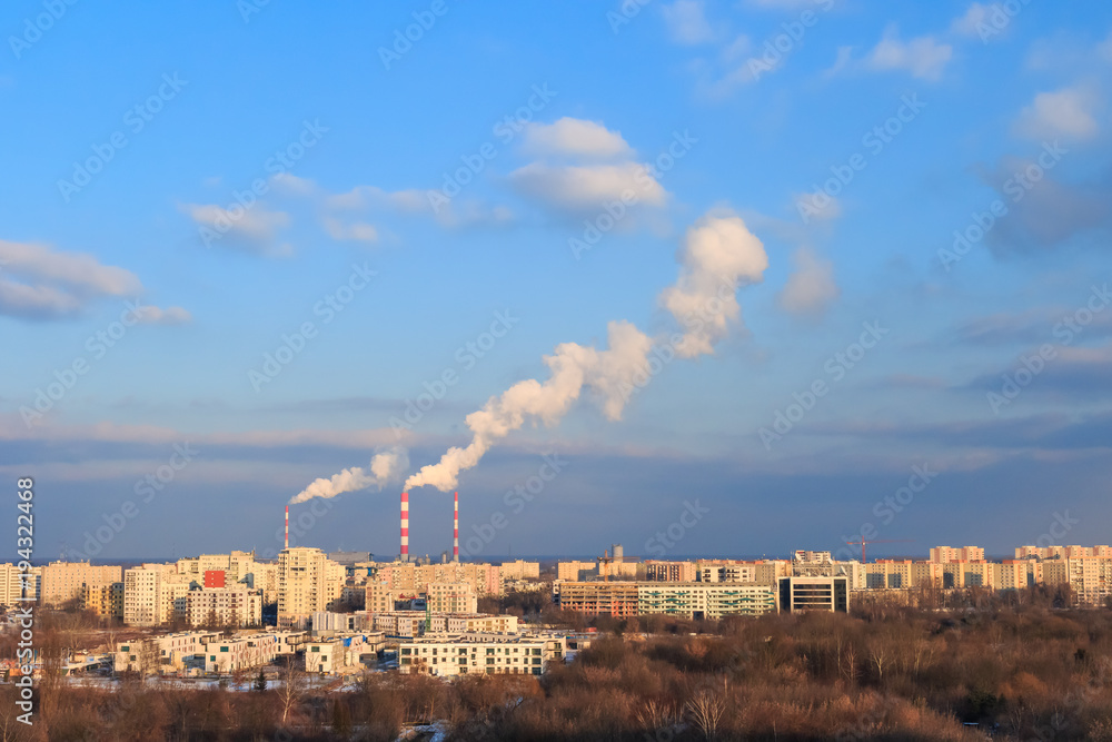 Warsaw skyline with smoking chimneys of the combined heat and power plant against the blue sky with white clouds on a sunny day.