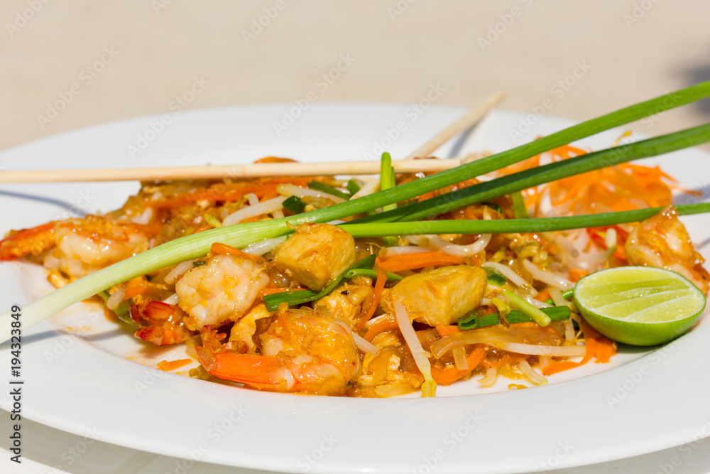 Tasty pad thai with shrimps, lemon and chopsticks, traditional food plate from Thailand Tasty pad thai with shrimps, lemon and chopsticks, traditional food plate from Thailand
