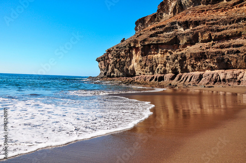 Calm water and blue sky in rustical beach Tiritaña. Bay framed by high cliffs in barranco near Taurito/Mogan. Between Punta de la Cruz de Piedra and Punta de los Medios Almudes. Gran Canaria