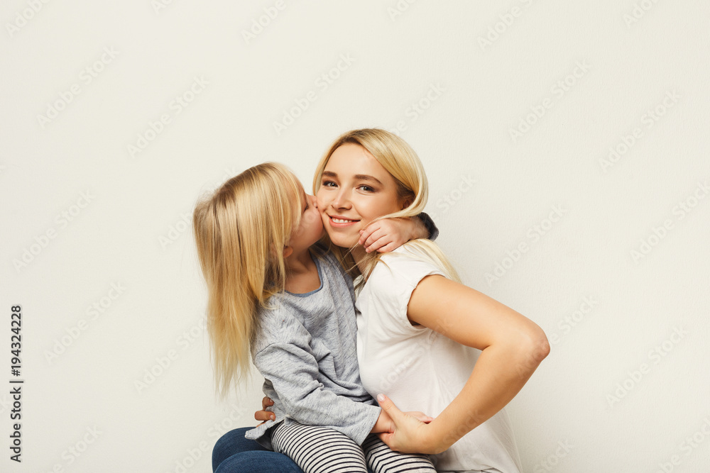 Obraz premium Happy mother and daughter embracing at white studio background