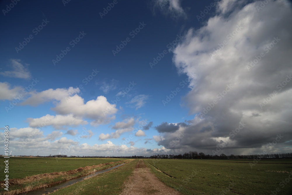 Big white clouds racing over the Zuidplaspolder in the Netherlands in blue sky Big white clouds racing over the Zuidplaspolder in the Netherlands in blue sky