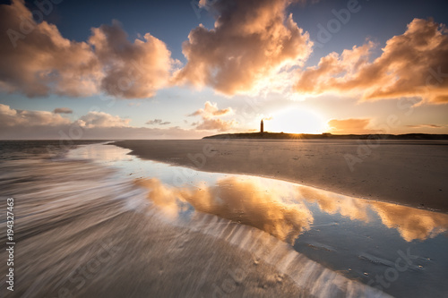 dramatic sunrise over North sea coast with lighthouse