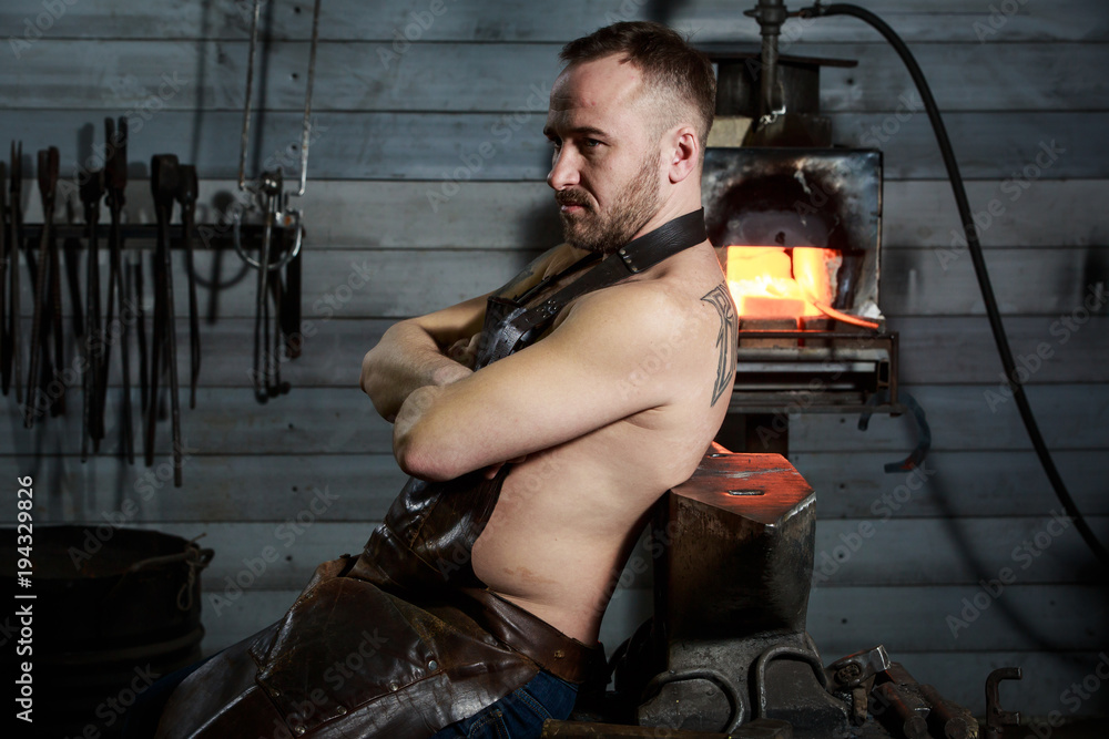Senior blacksmith forging the molten metal on the anvil in smithy. Senior blacksmith forging the molten metal on the anvil in smithy.