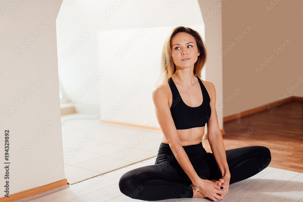 Young sporty woman practicing yoga at home, sitting in Butterfly exercise Young sporty woman practicing yoga at home, sitting in Butterfly exercise