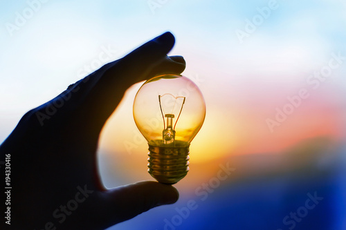 light bulb in hand at sunset