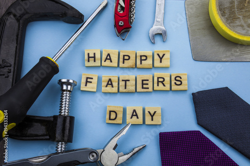 Happy Fathers Day message on a blue background with frame of tools and ties. photo