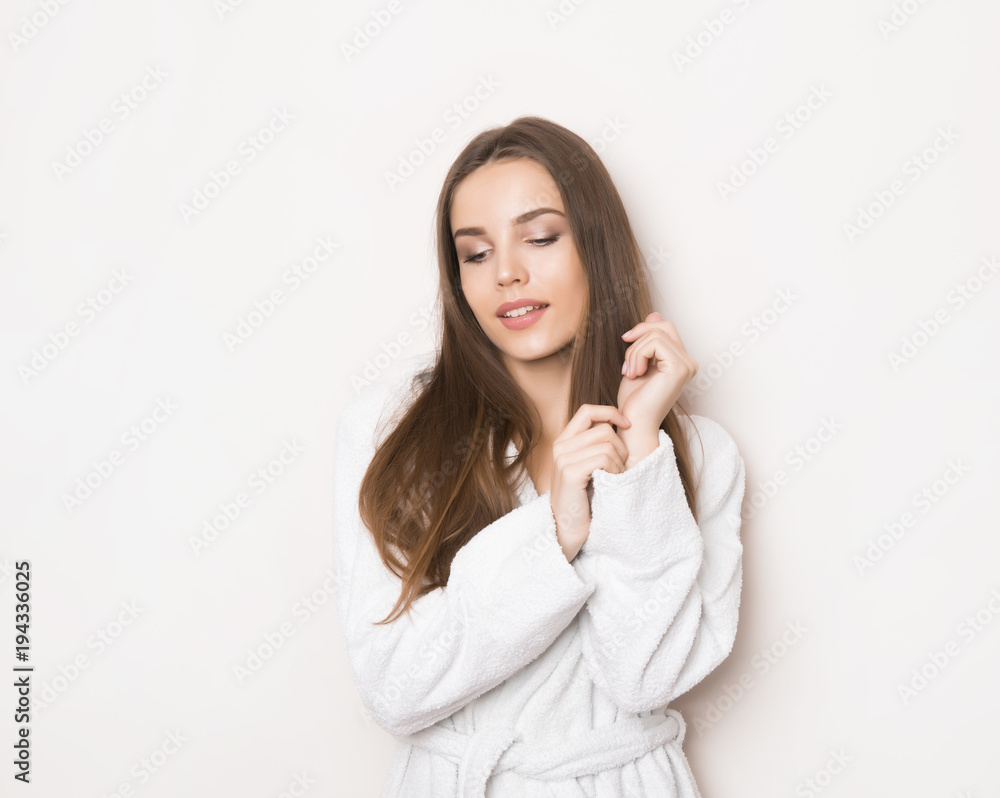 beautiful young woman with long hair wearing bath robe and posing on grey background with copy space beautiful young woman with long hair wearing bath robe and posing on grey background with copy space