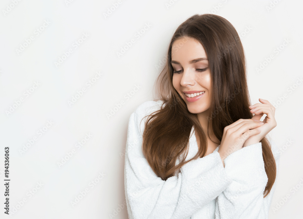 beautiful young woman with long hair wearing bath robe and posing on grey background with copy space beautiful young woman with long hair wearing bath robe and posing on grey background with copy space