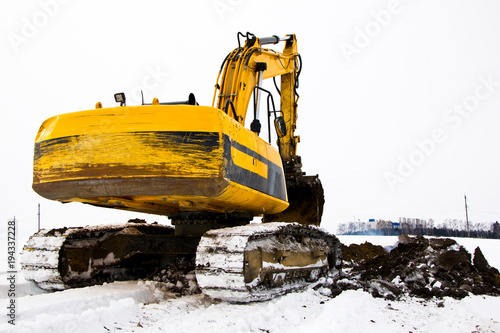 Caterpillar excavator digs trench in frozen soil