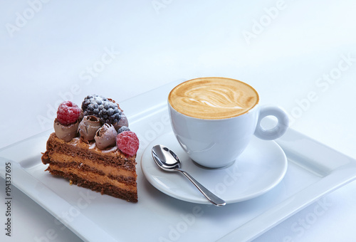 The piece of chocolate pie wieh wild berries served with the cup of exellent capucino photo