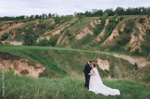 The newlyweds stand with each other. Against the backdrop of hills and mountains. Wedding.