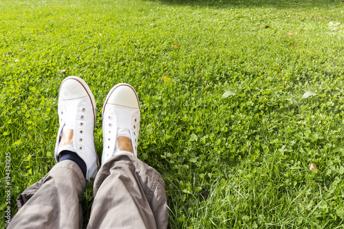 Close-up of sneakers worn by a man sitting on the grass