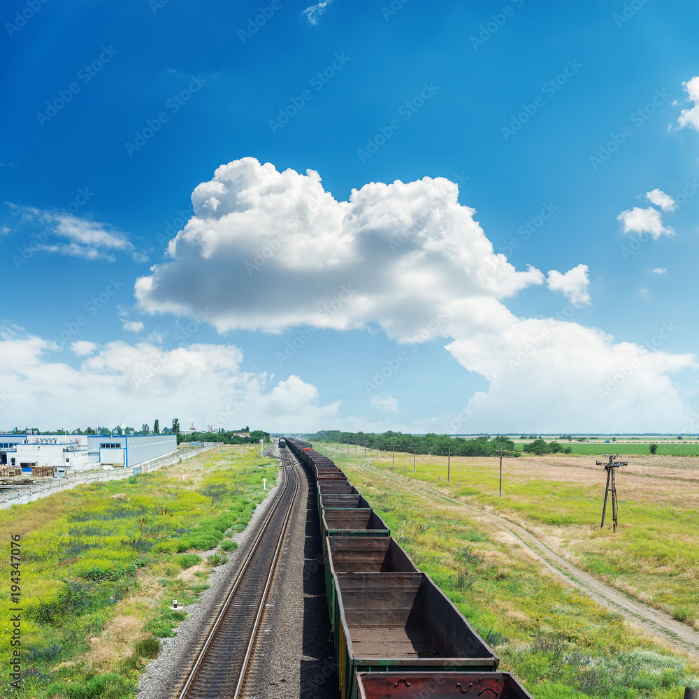 railroad with empty wagons and clouds in blue sky