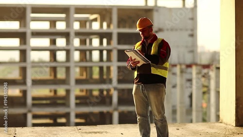 Master-builder with documentation on project site. Worker makes notes in his business papers. Building inspector writes in his documentation