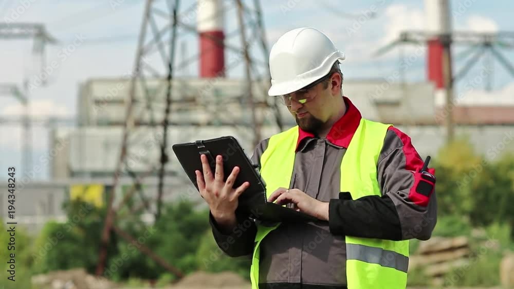 Power engineering specialist with personal computer at heat electric power station. Worker in hard hat at heat electric power station, engineering supervision. Worker with computer at power station Power engineering specialist with personal computer at heat electric power station. Worker in hard hat at heat electric power station, engineering supervision. Worker with computer at power station