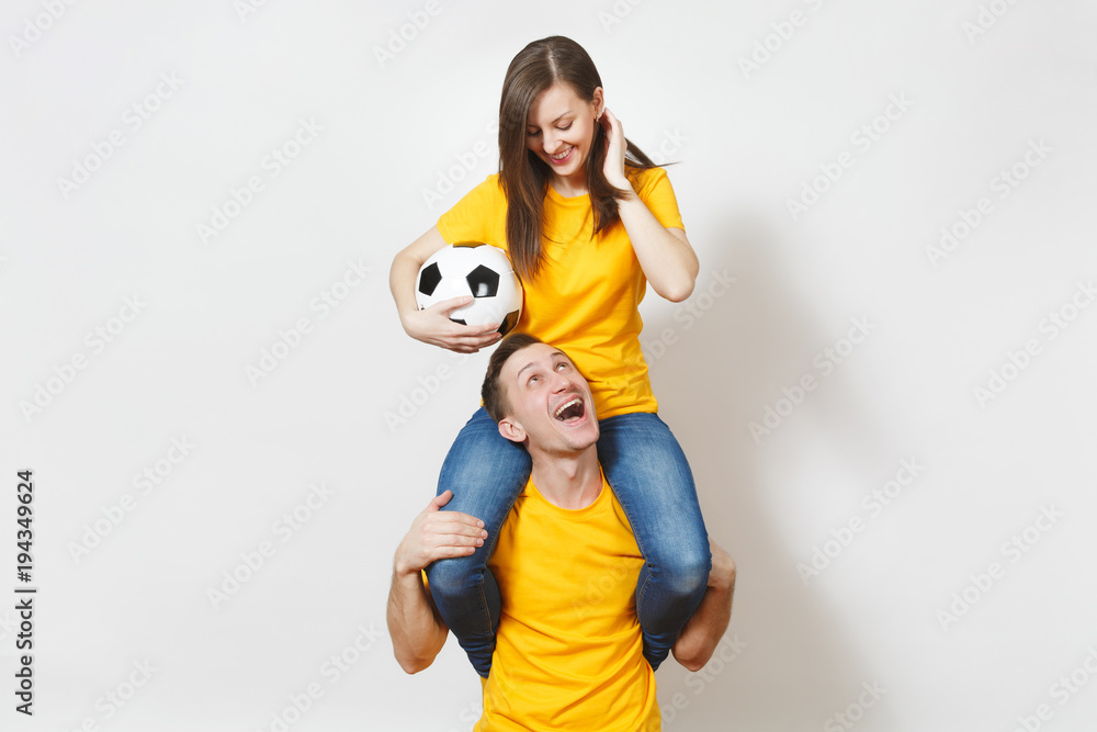 Inspired young couple, woman sit on man shoulders, fans with soccer ball cheering favorite football team expressive gesticulating hands isolated on white background. Family leisure, lifestyle concept.