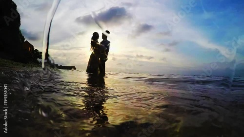 Love couple at sunset in a sea embracing silhouette