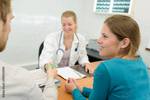 expectant couple talking while counsulting doctor in clinic
