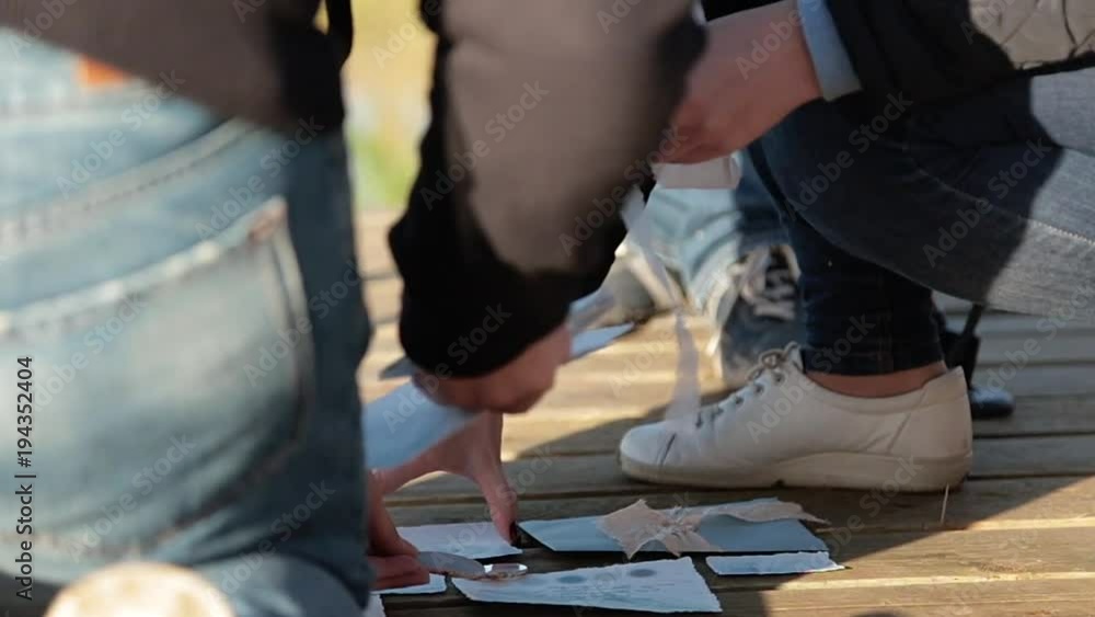 People lay out wedding poligraphic cards at wooden desk floor People lay out wedding poligraphic cards at wooden desk floor