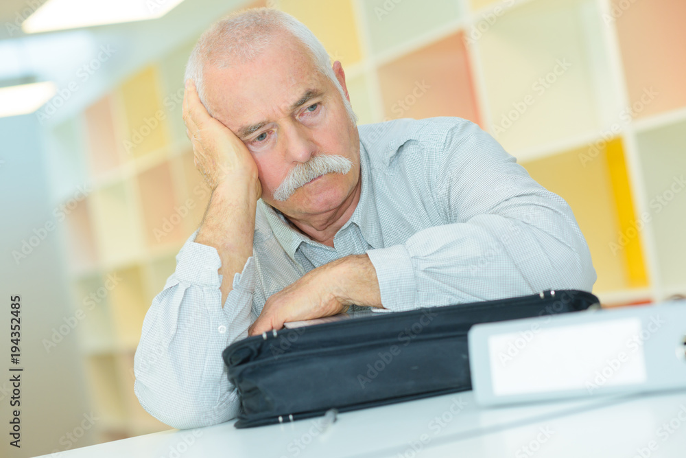 Fototapeta premium sad senior man sitting at table at the office
