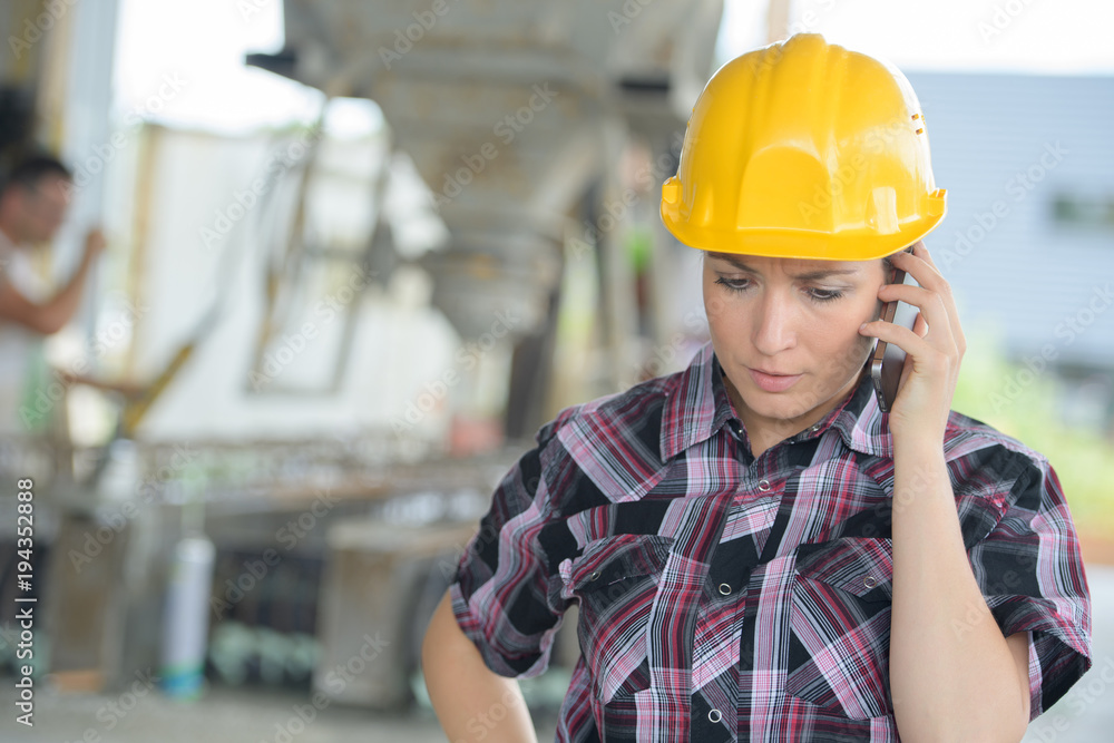 young woman wearing a hardhat talking on the phone young woman wearing a hardhat talking on the phone