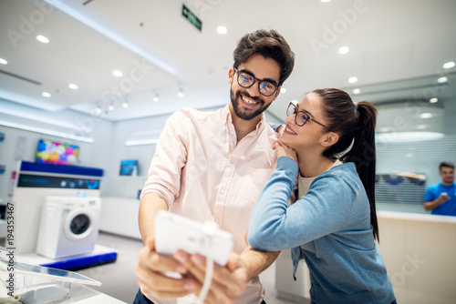 Multicultural couple testing the new model of a tablet in the tech store. Customers in shopping looking for a new tablet.