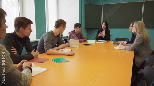 Group of students and a teacher sit at a table and talk