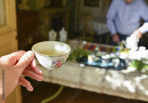 Photography A female hand holds a porcelain mug with green tea