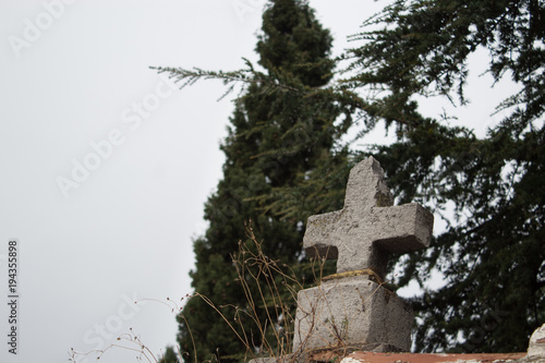 Old broken religious cross with trees as background