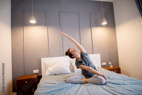Vászonkép Attractive shape sporty middle aged woman doing seated yoga poses on the bed before sleeping