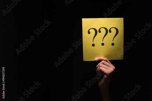 Canvas Print hand holding a yellow paper with question mark in a dark background