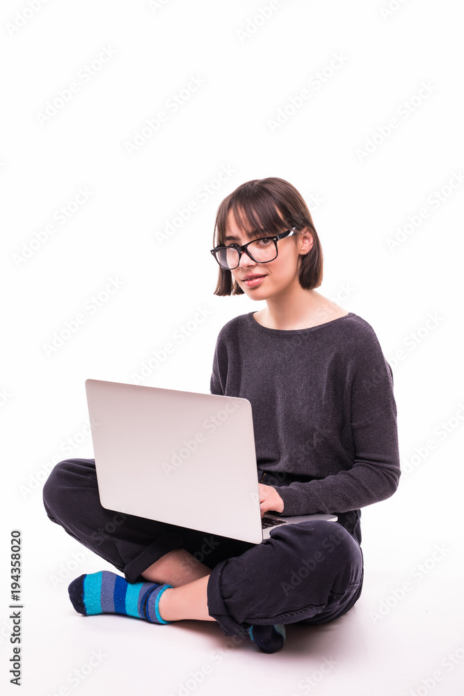 Pretty young teen girl sitting on the floor with crossed legs and using laptop isolated over white background Pretty young teen girl sitting on the floor with crossed legs and using laptop isolated over white background