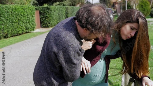 Man trying to help pregnant woman with contractions enter car slow motion