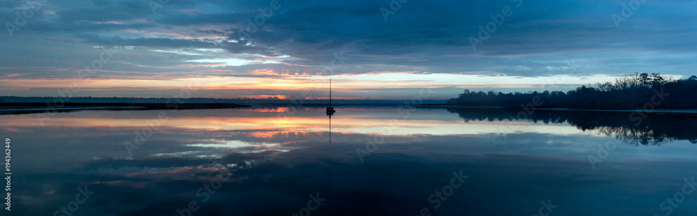A calm morning at sunrise with a sailboat ready to depart for the day. A calm morning at sunrise with a sailboat ready to depart for the day.