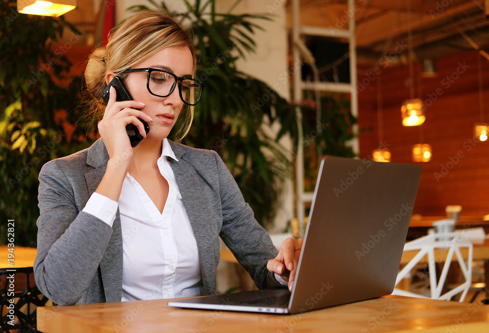 A young attractive business woman sitting in a cafe with a lapto A young attractive business woman sitting in a cafe with a lapto