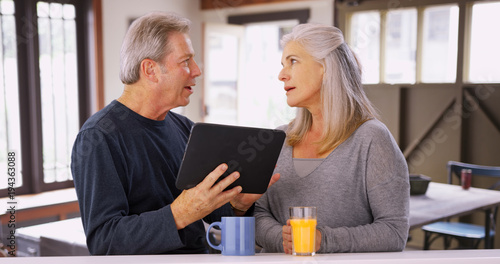Elderly caucasian couple looking at tablet computer during breakfast