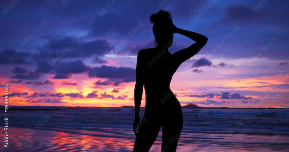 Single silhouette of sensual woman standing on sunset beach in Hawaii
