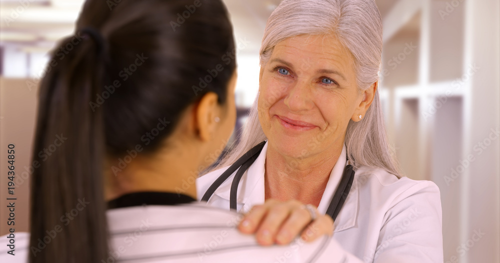 A happy doctor talks to a patient at the hostpital. A young patient talks to her elderly doctor A happy doctor talks to a patient at the hostpital. A young patient talks to her elderly doctor