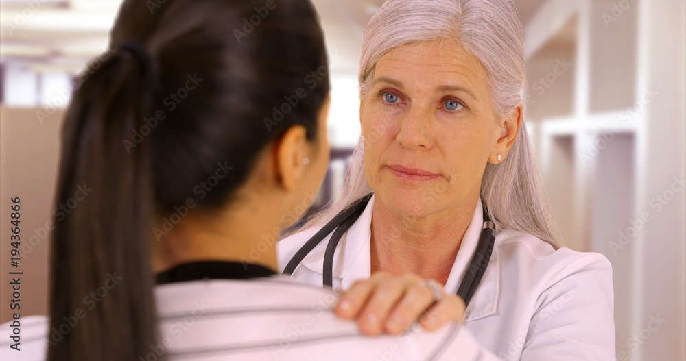 A happy doctor talks to a patient at the hostpital. A young patient talks to her elderly doctor A happy doctor talks to a patient at the hostpital. A young patient talks to her elderly doctor