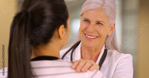 A smiling doctor talks to one of her patients. A patient talks to her older doctor 